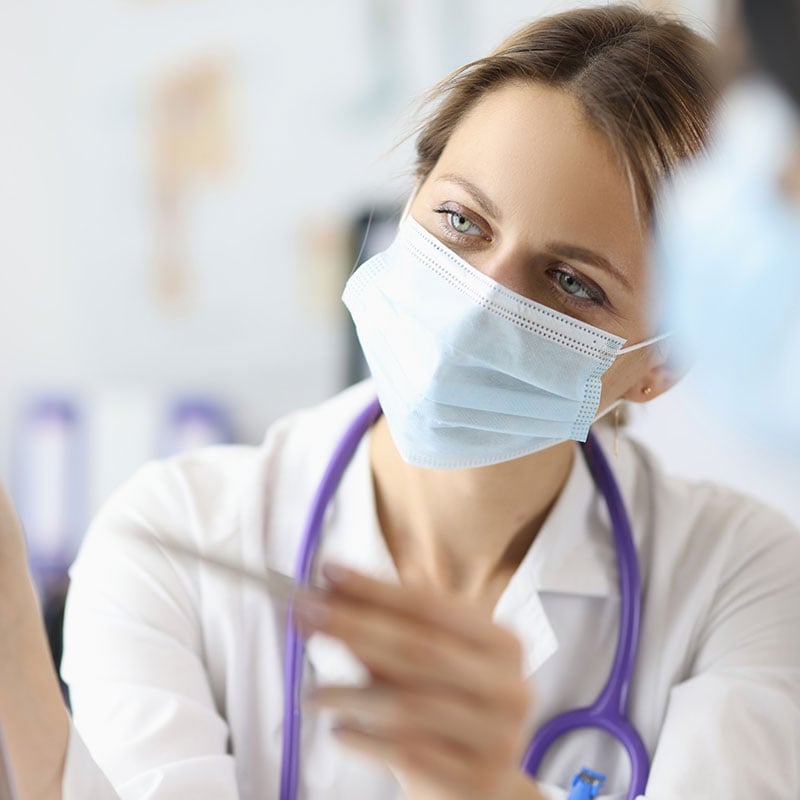 Doctor wearing a mask pointing at an x-ray