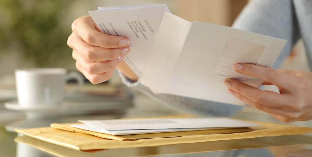 A person opening an envelope and pulling out a letter A person opening an envelope and pulling out a letter