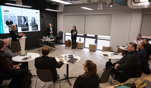 A group of people watch a short presentation at a CDS roundtable event