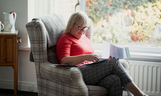 Woman sat in a chair reading her mail