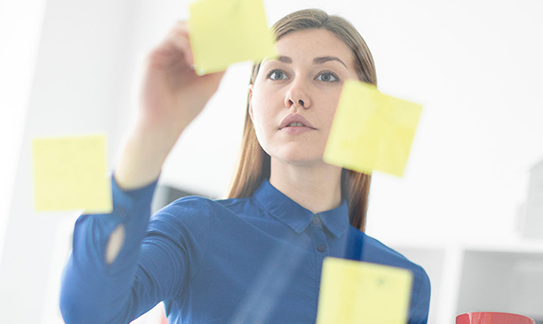 Woman arranging sticky notes on glass Woman arranging sticky notes on glass
