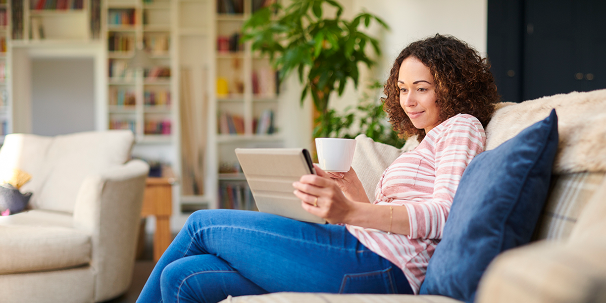 Woman sat on her sofar using a digital tablet.