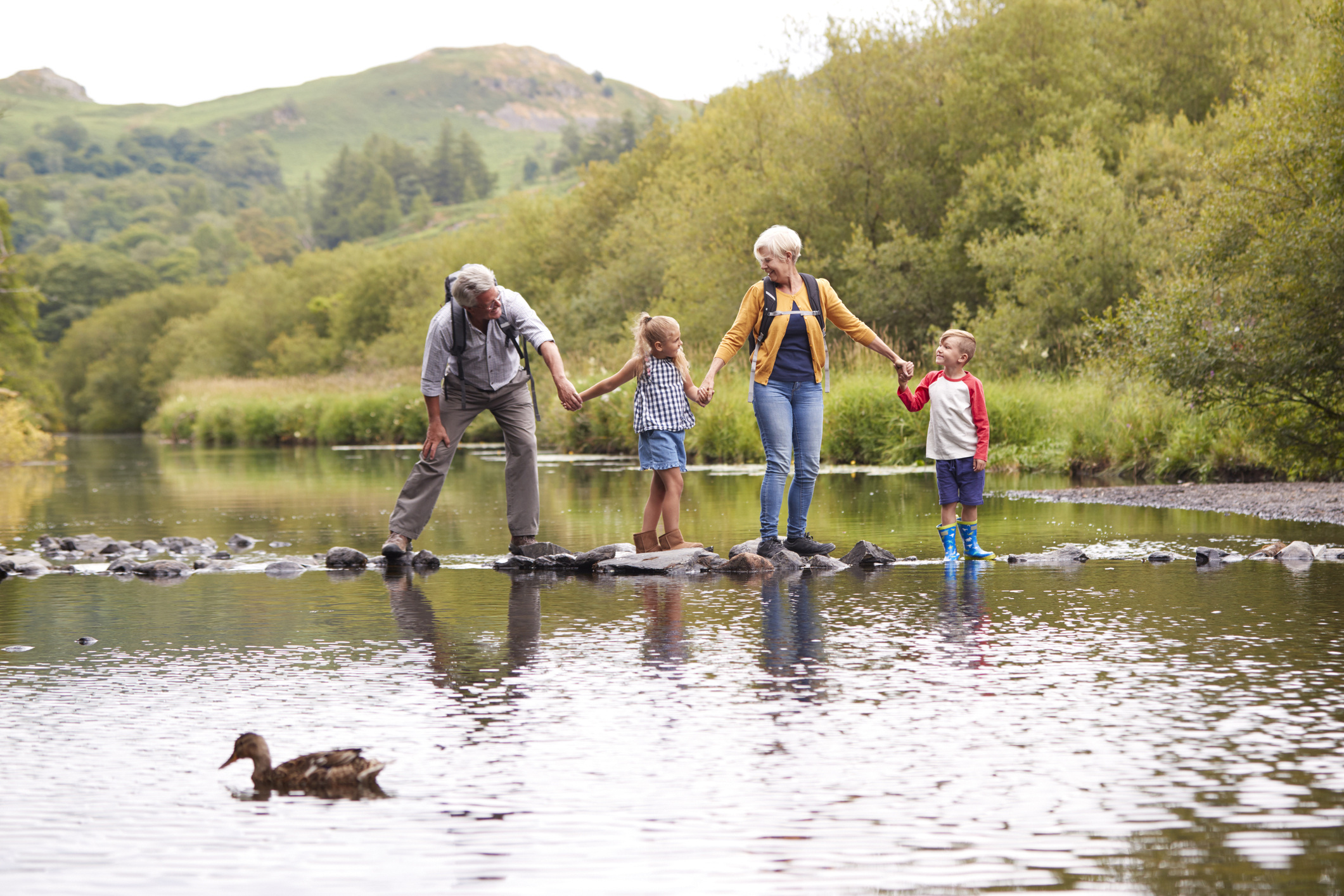 Grandparents with Grandchildren crossing a river whilst hiking in the Lake District.
