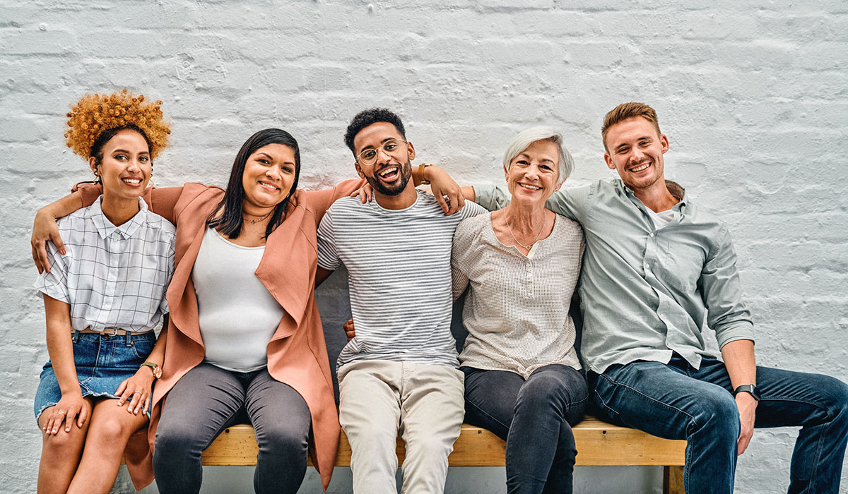 A group of people sitting with their arms around each other in the office A group of people sitting with their arms around each other in the office