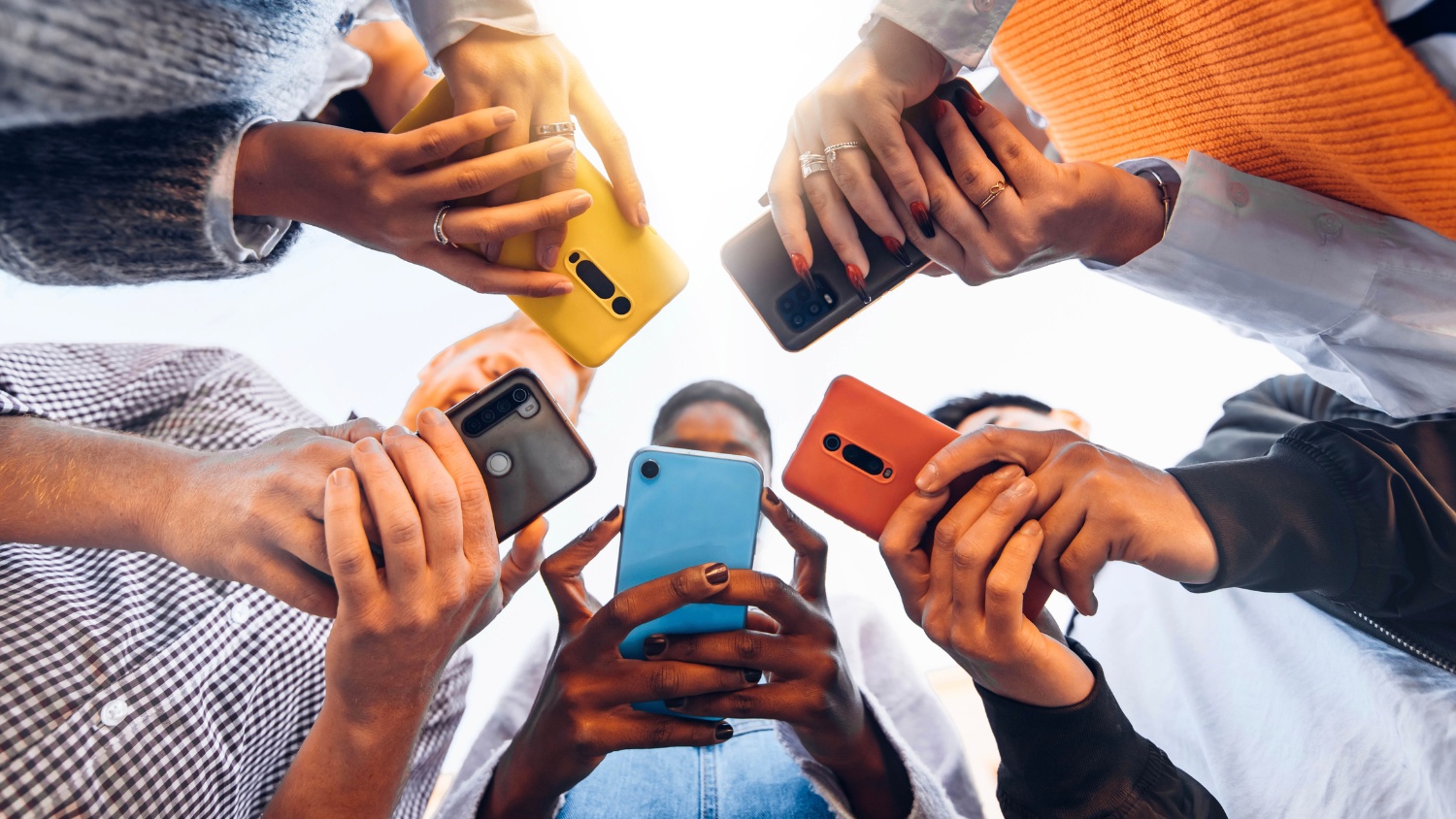 Teens in circle holding mobile phones