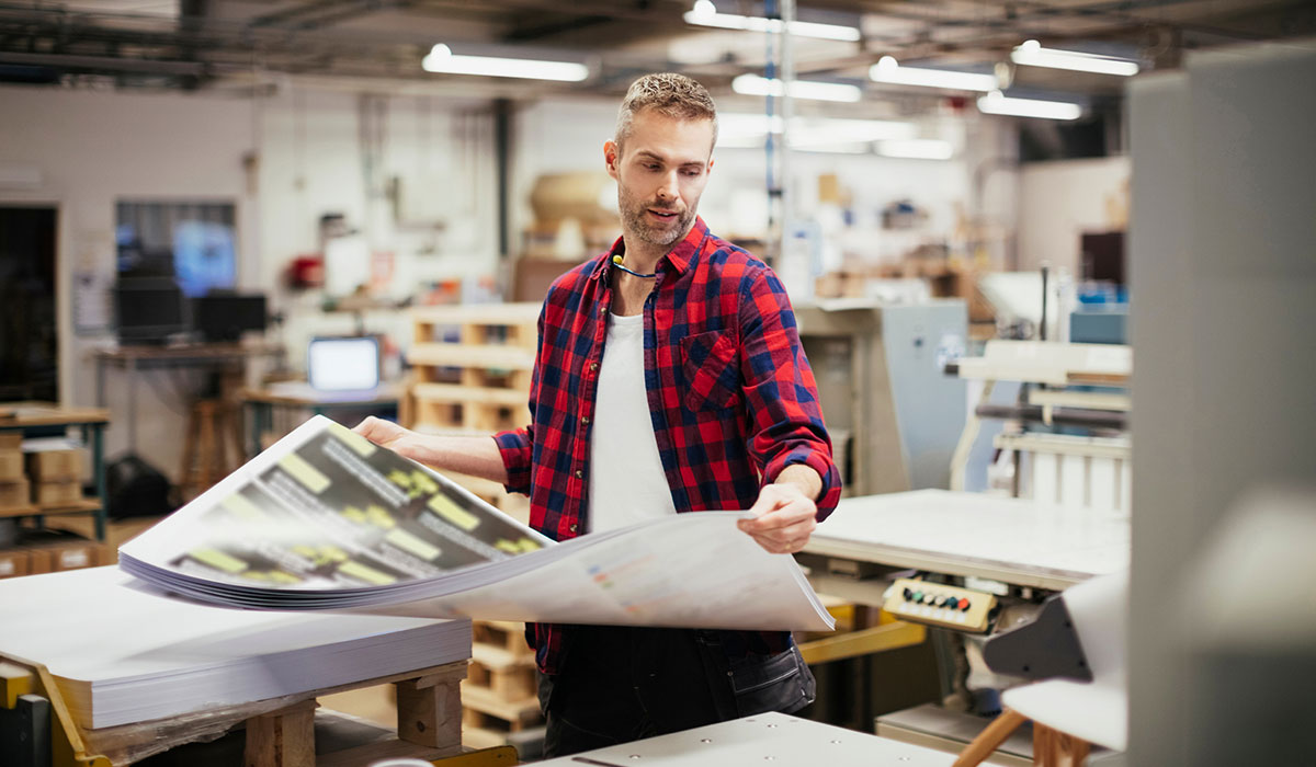 Person holding pile of printed papers in a print factory