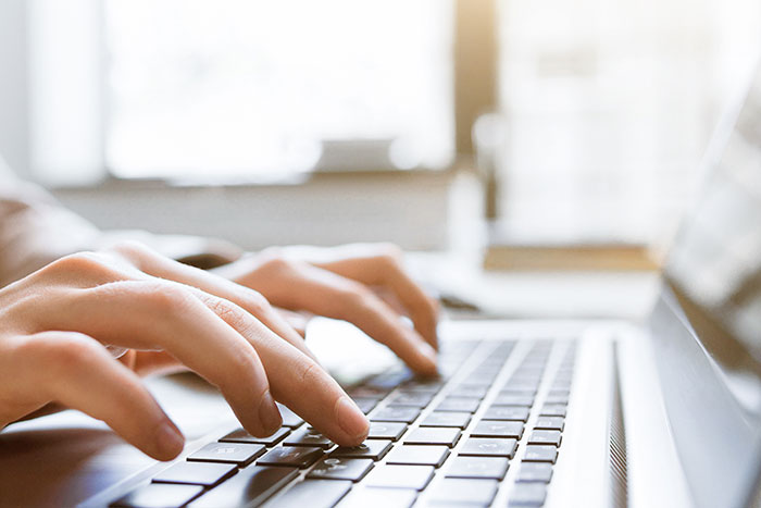 Close up image of hands typing on a keyboard