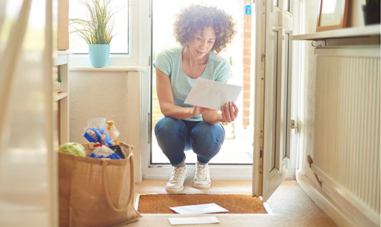 Woman crouched down in doorway looking at mail Woman crouched down in doorway looking at mail