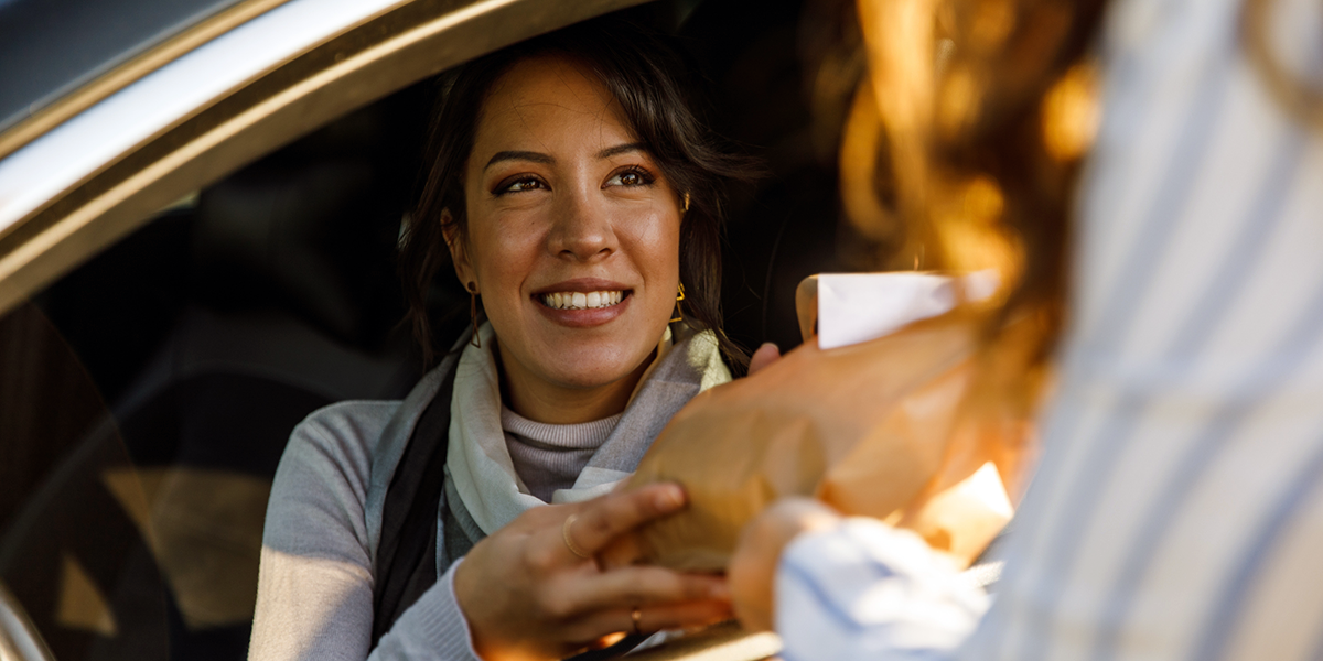 Woman receiving a food order through her car window.