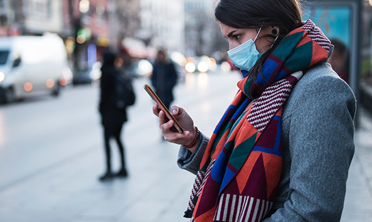 Woman wearing medical mask looking at her phone